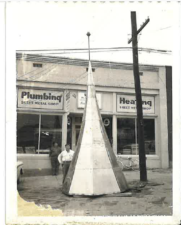Historic plumbing, heating, and sheet metal shop with a large fabricated metal structure displayed outside.