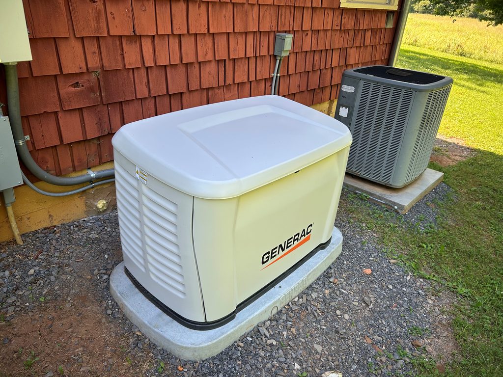 Generac standby generator installed on a concrete pad beside a home and outdoor air-conditioning unit.